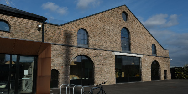 Historical red brick building with large glass windows in arched shapes.